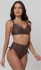Uma mulher de frente, com cabelos escuros vestindo um biquíni marrom. Top estruturado com aro e bojo, sendo um sutiã meia taça. A calcinha é de cintura alta hot pant com cordões laterais para amarração detalhados. O fundo é cinza neutro. 