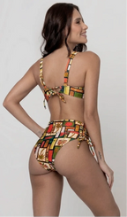 Uma mulher de costas, com cabelos escuros vestindo um conjunto de biquíni de duas peças. O biquíni tem uma estampa colorida com temas tropicais e ícones. Top estruturado com aro e bojo, sendo um sutiã meia taça. A calcinha é de cintura alta hot pant com cordões laterais para amarração detalhados. O fundo é cinza neutro. 