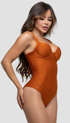 Modelo feminina de cabelos claros, de lado, em um estúdio com fundo neutro, vestindo um maiô cobre com efeito modelador. A peça é confeccionada em tecido de poliamida e elastano, com proteção solar. Maiô estruturado com sutiã meia taça com aro para sustentação, bojo, decote coração e amarração nas costas estilo espartilho.