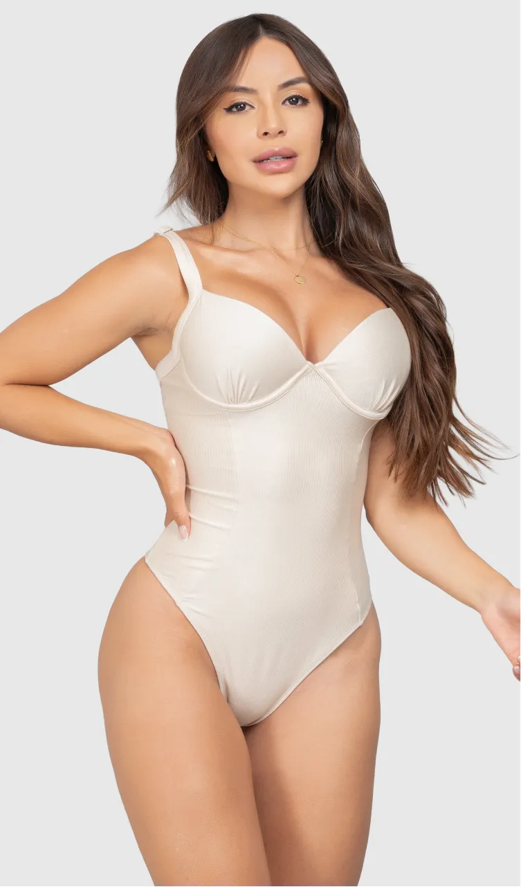 Modelo feminina de cabelos claros, de frente, em um estúdio com fundo neutro, vestindo um maiô branco com efeito modelador. A peça é confeccionada em tecido de poliamida e elastano, com proteção solar. Maiô estruturado com sutiã meia taça com aro para sustentação, bojo, decote coração e amarração nas costas estilo espartilho.