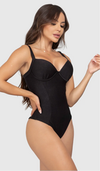 Modelo feminina de cabelos claros, de lado, em um estúdio com fundo neutro, vestindo um maiô preto com efeito modelador. A peça é confeccionada em tecido de poliamida e elastano, com proteção solar. Maiô estruturado com sutiã meia taça com aro para sustentação, bojo, decote coração e amarração nas costas estilo espartilho.